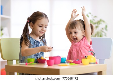 Children Playing With Plastic Tableware At Home Or Daycare Center