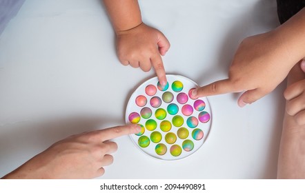 Children Playing With Push Pop Fidget Toy On The Floor