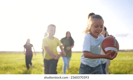 children playing rugby in the park. group of children play american football run outdoors in the park in summer. happy family kid dream concept. family children play american lifestyle football run - Powered by Shutterstock