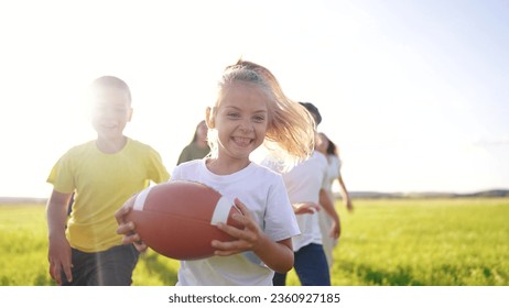 children playing rugby in the park. group of children play american football run outdoors in the park in summer. happy family kid dream concept. family children play american football run lifestyle