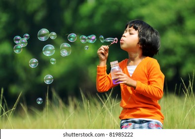 Children playing with soap bubbles on a green environment background - Powered by Shutterstock