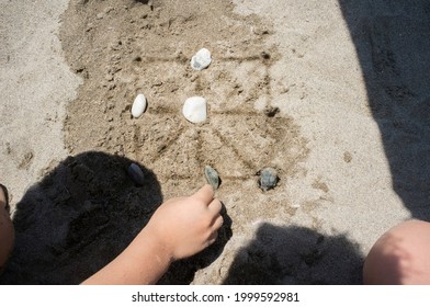 Children Playing Tic-tac-toe With Natural Board Made With Sand Marks And Beach Pebbles. Overhead View