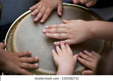 Children playing together at djembe drum, close up
