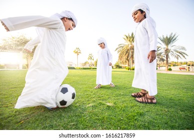 Children Playing Together In Dubai In The Park. Group Of Kids Wearing Traditional Kandura White Dress From Arab Emirates