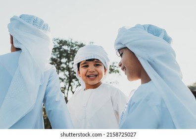 Children Playing Together In Dubai In The Park. Group Of Kids Wearing Traditional Kandura White Dress From Arab Emirates