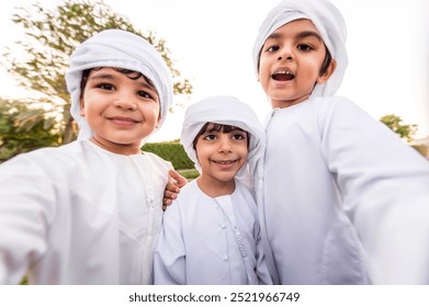 Children playing together in Dubai in the park. Group of kids wearing traditional kandura white dress from arab emirates - Powered by Shutterstock