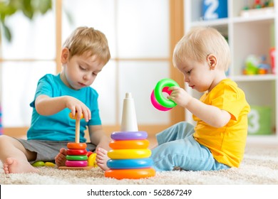Children Playing Together. Toddler Kid And Baby Play With Blocks. Educational Toys For Preschool And Kindergarten Child. Little Boys Build Pyramid Toys At Home Or Daycare.