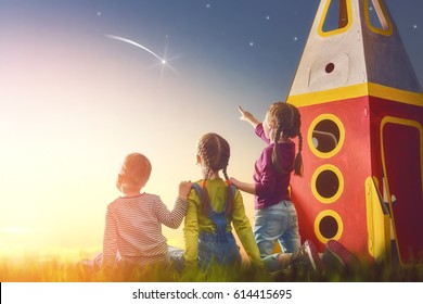 Children playing with toy rocket and dreaming of becoming a spacemen. Portrait of funny kids looking at the sky. Family friends games outdoors. Boy and girls make a wish by seeing a shooting star.