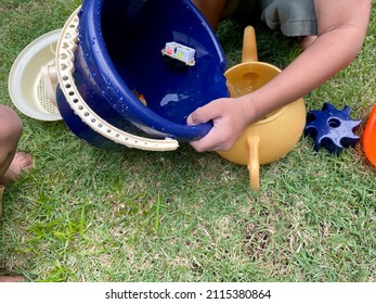 Children Playing With Toys, With One Kid Pouring Water Into A Plastic Teapot. Early Education Concept