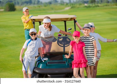 Children posing near golf car at golf course at summer day