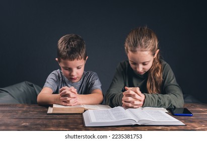 Children pray with folded hands. The Bible is open on the table. Prayer to pray. Teenagers - Powered by Shutterstock