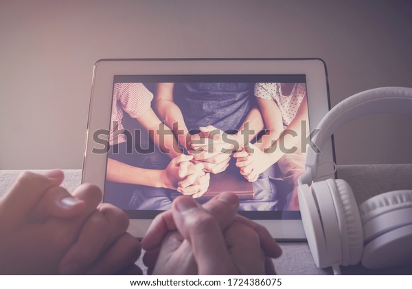 Children praying with father parent\
with laptop, family and kids worship online together at home,\
streaming online church service, social distancing\
concept