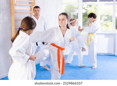 Children pupils train to perform defensive karate installations and attacking actions for combat techniques classes. Teenagers prepare for competition, with guidance of coach repeat combat skills - Powered by Shutterstock