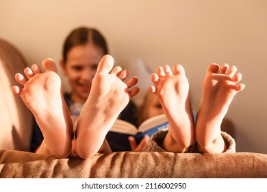 Children read book. Kids feet barefoot at home. Kids Sisters have fun playing with their feet. Selective focus. Happy holidays. April Fools' Day. World book day.