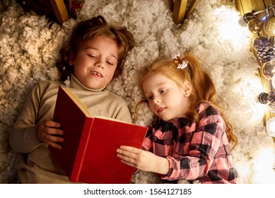 Children Are Reading A Book In A Decorated Room For Christmas.