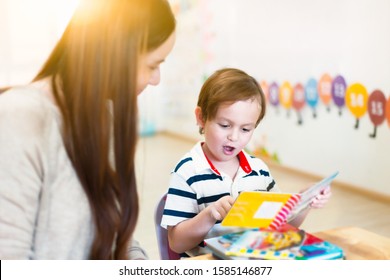 Children reading a book with teacher in a classroom. Children and learning concepts.