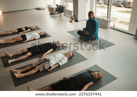 Children relax lying down to the sounds of a Tibetan bowl in the fitness room. Children's yoga