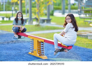 Children Ride On See Saw In Park Playground.Asian Siblings Playing On Healthy Outdoor Recreational Equipment.Childhood And Friendship.Young Girls And Boy Play In School Yard.Climbing.