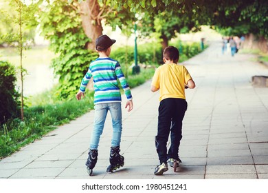 Children Riding On Scooter And Roller Skate At Street. Back View Of Friends Spending Time Together Outside. Active Outdoor Sport For Kids. Friendship, Leisure And Lifestyle Concept.