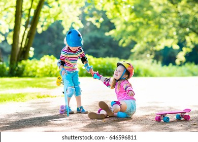 Children riding skateboard in summer park. Little girl and boy learn to ride skate board, help and support each other. Active outdoor sport for kids. Child skateboarding. Preschooler kid skating.