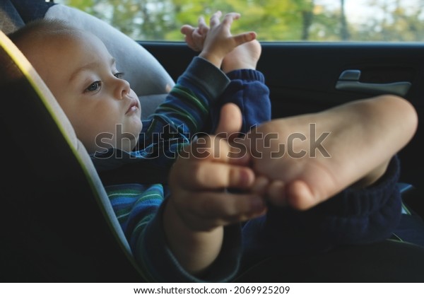 Children road\
safety concept. Toddler boy traveling in car sitting in child\
safety seat with seat belts fastened.\
