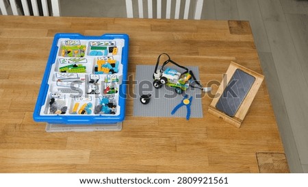 Children robotics STEM education constructor kit on wooden table. Plastic storage box, sorted bricks, machine model. Home engineering activity theme. Smart Screen Time for Kids. Fine Motor Development