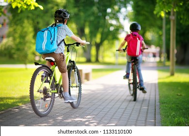 Kinder mit Rucksacksack fahren im Park in der Nähe der Schule. Schüler mit Rucksäcken im Freien
