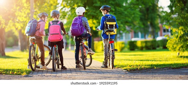 Children with rucksacks riding on bikes in the park near school. Pupils with backpacks outdoors - Powered by Shutterstock