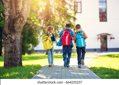 Children with rucksacks standing in the park near school. Pupils with books and backpacks outdoors