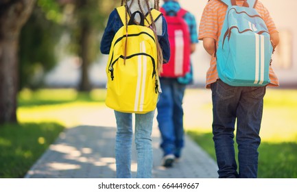 Children with rucksacks standing in the park near school. Pupils with books and backpacks outdoors