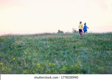 Children run across the field in summer among wildflowers, a sense of freedom, a happy childhood surrounded by nature, hiking, family holidays in the country - Powered by Shutterstock