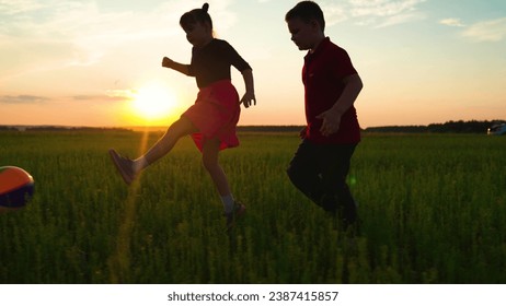 Children run after ball on green grass. Happy family, children at sunset in park play football together. Happy kids playing with ball in park. Children team. Sport Group kids in nature playing ball - Powered by Shutterstock