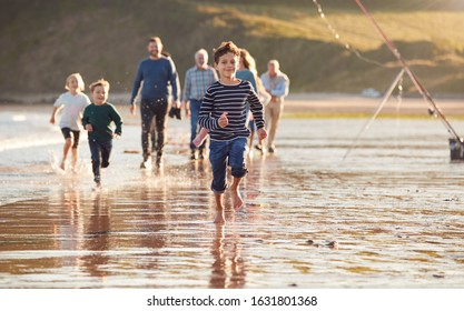 Children Run Ahead As  Multi-Generation Family Walk Along Shore On Winter Beach Vacation