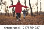 children run in the forest in autumn park. happy family kid dream concept. group of children in jackets in the fall run in a park in the forest. freedom childhood nature concept