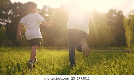 children run in the park. boy and a girl holding hands run through the grass in the summer at sunset in the park. happy family kid dream concept. children run at sunset in summer hold hands sun - Powered by Shutterstock