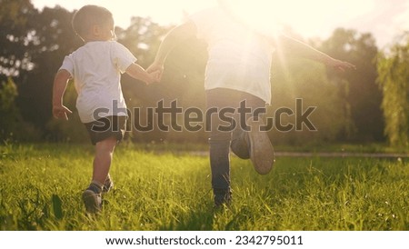 children run in the park. boy and a girl holding hands run through the grass in the summer at sunset in the park. happy family kid dream concept. children run at sunset in summer hold hands sun