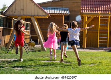 Children Run To The Playground. Four  Little Girls  Run To Play On The Playground. Taken From The Back  Kids Run To Play