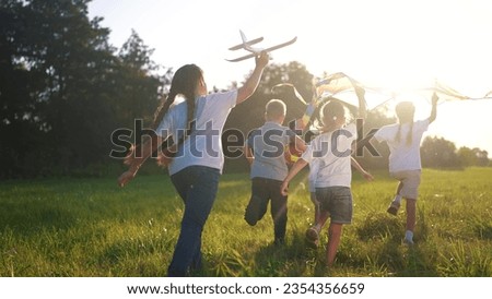 children run through the meadow in park with toys in their hands. happy family kid dream concept. a group of little kids have fun together and play with flying kites toy lifestyle airplane