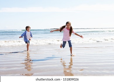 Children Running Away From Breaking Waves On Beach