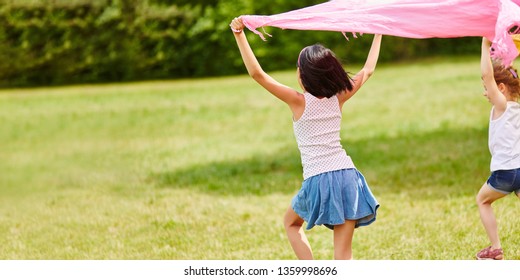 Niños corriendo con tela en el aire en verano