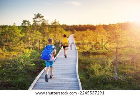 Children running on the boardwalk on bog. Concept of hiking, vacation and friendship.