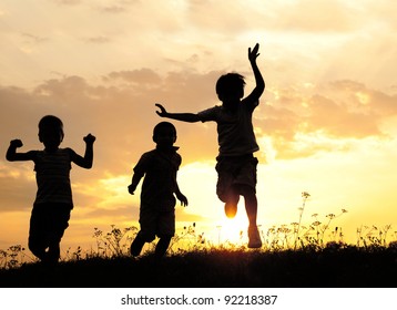 Children Running On Meadow At Sunset