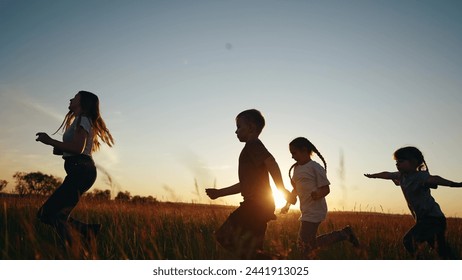 Children running in park at sunset. happy family kindergarten kids dream concept. Kids running in grass silhouette. Children lifestyle playing outdoors silhouette. Kids playing in park at sunrise - Powered by Shutterstock