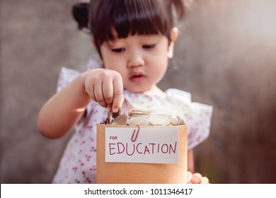 Children With Saving Money For Education Concept. 2 Years Old Child Putting Coin Into A Box