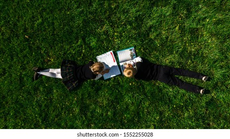 Children, In School Form, Reading The Book On The Grass In Summer. Top View