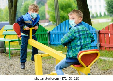 Children School In Medical Masks Play At A Quarantine Playground During A Coronavirus Pandemic