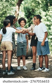 Children, scout and hand stack in forest for support, teamwork and motivation in nature. Kids, friends and huddle with unity gesture for collaboration, solidarity and celebration of wilderness skills