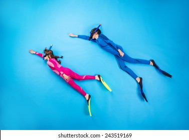 Children scuba diving deep in the sea. Studio shot on a blue background. - Powered by Shutterstock