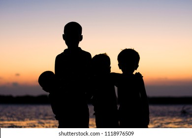 Children silhouettes at the beach at sunset