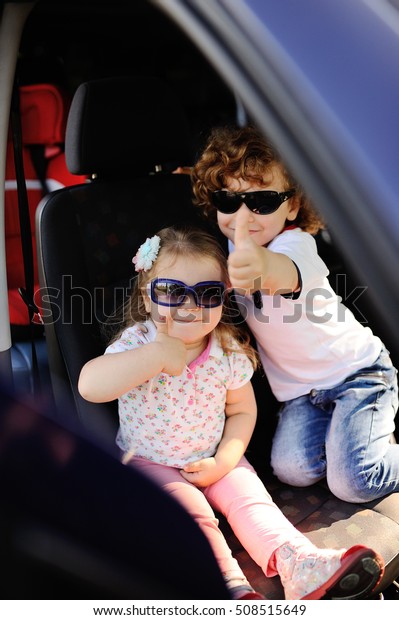 children sit in the car and play. little boy and\
girl in sunglasses laugh in the\
car